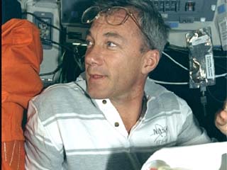 Commander Terrence Wilcutt at the command station consults rendezvous documents on the flight deck of the Space Shuttle Endeavour.